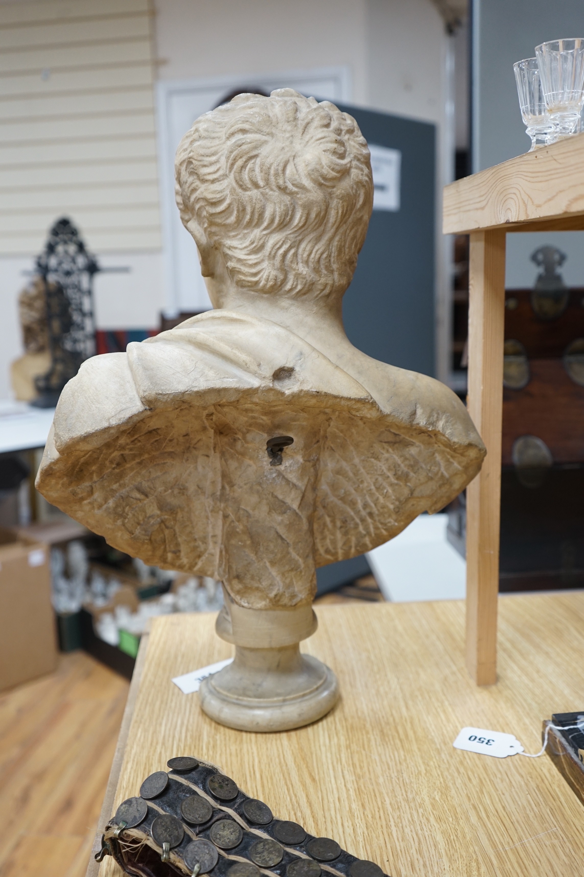 After the Antique marble bust of a Roman man wearing a Chlamys with a buckle at the shoulder, later socle and repairs, 54cm tall